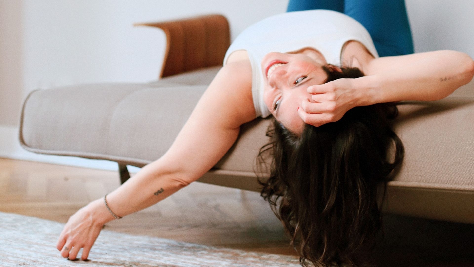 Portraitaufnahme einer lachenden Frau auf einem Sofa im Beyond & Bloom Studio 51 mit weichem Tageslicht und entspannter Editorial-Atmosphäre.