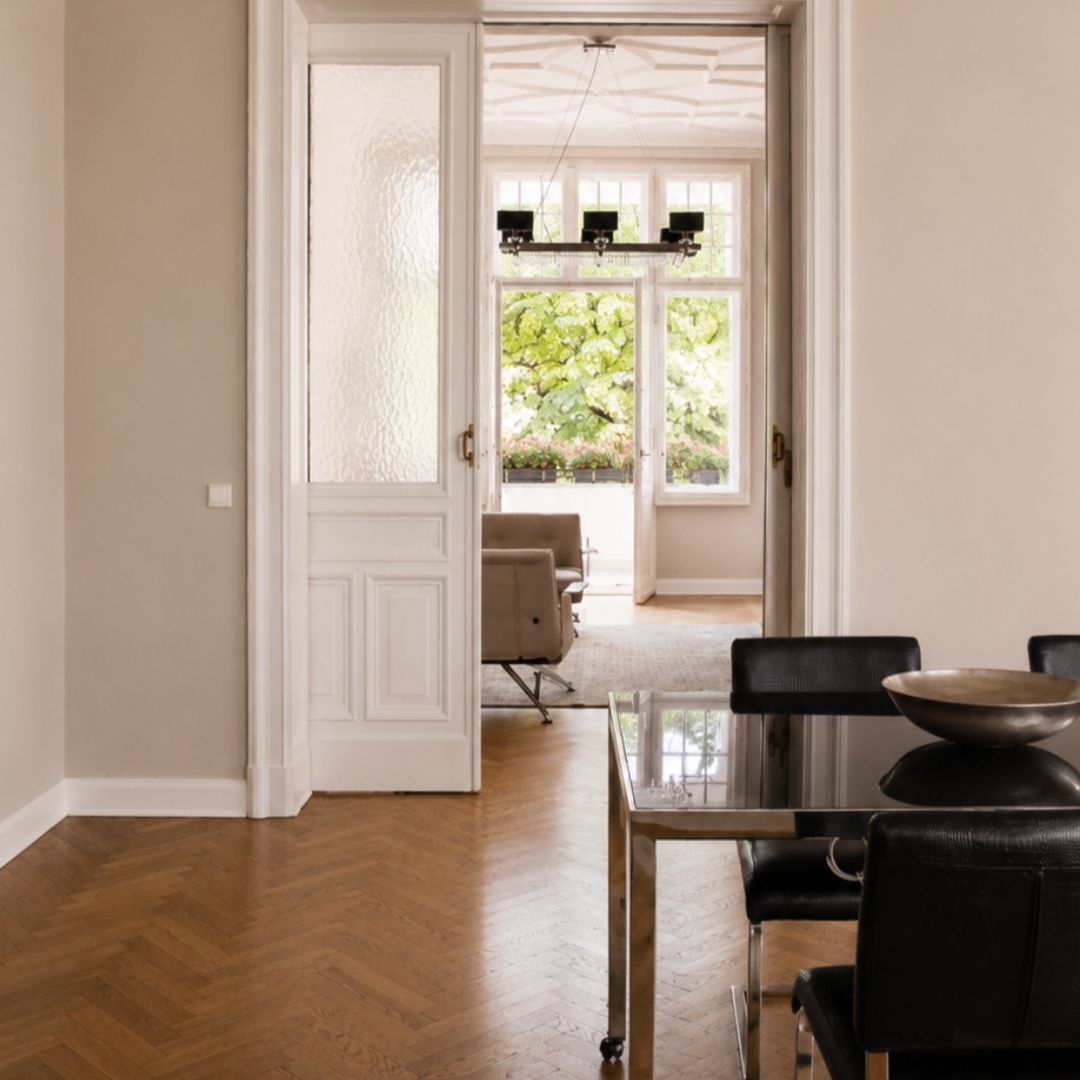 Blick durch den Meetingraum in den Lounge-Bereich von Beyond & Bloom Studio 51 mit Altbautüren, Parkettboden, hohen Fenstern und Tageslicht.